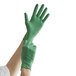 A person wearing a green Showa biodegradable nitrile glove.