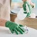 A person wearing Showa green biodegradable nitrile gloves cleaning a table.