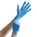 A person putting on a blue Showa nitrile glove.