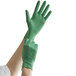 A person wearing Showa green biodegradable nitrile gloves on their hand.