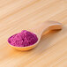A wooden spoon filled with dragon fruit powder.