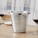 A silver Acopa wine tasting spittoon on a table.