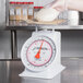 A gloved hand uses a Cardinal Detecto T-25-KP scale to weigh a dough ball.