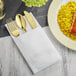 A white linen pocket fold napkin with gold cutlery on a plate of rice and meat.