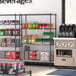 A Steelton wire shelving kit with black shelves holding beverages in a convenience store.