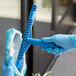 A person in blue gloves using a Lavex Pro blue window cleaning tool.