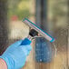 A hand in a blue glove cleaning a window with a Lavex window squeegee.