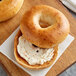 A frozen Original New York Style onion bagel with cream cheese on top.