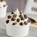 A cup of ice cream with dark chocolate raspberry truffle cups on top.
