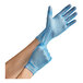 A person's hands wearing Noble Products blue vinyl gloves.