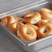 A metal tray of Original Bagel mini bagels on a table in a school kitchen.