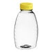 A clear plastic Classic Queenline honey bottle with a yellow flip top lid.