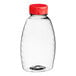 A clear plastic Classic Queenline honey bottle with a red cap.