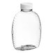 A clear plastic Queenline honey bottle with a white cap.