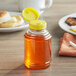 A 12 oz. Skep PET bottle of honey with a yellow cap on a table.