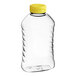 A clear plastic 16 oz. ribbed hourglass honey bottle with a yellow flip top lid.