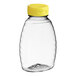 A clear plastic Classic Queenline honey bottle with a yellow lid.