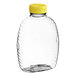 A clear plastic Queenline honey bottle with a yellow flip top lid.