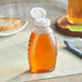 A Classic Queenline PET honey bottle with a white lid on a table.