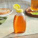 A Classic Queenline PET honey bottle with yellow cap on a table.