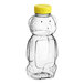 A 16 oz. clear plastic Bear Honey bottle with a yellow flip top lid.