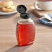 An 8 oz. Classic Queenline PET honey bottle with black cap on a table.