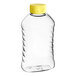 A clear plastic 16 oz. Ribbed Hourglass PET honey bottle with a yellow cap.