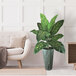 A 48" artificial Dieffenbachia plant in a copper washed metal planter on a wood surface next to a white couch.