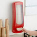 A hand using a red Tork Xpressnap napkin dispenser on a counter.
