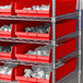 A shelf with Regency red shelf bins holding white objects.