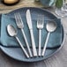 Acopa Phoenix stainless steel flatware set on a blue napkin with a fork and spoon.