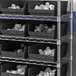 A metal shelf with Regency black plastic bins.