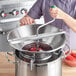 A woman uses a Garde heavy-duty stainless steel rotary food mill to make tomato sauce in a large metal pot.