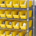 A shelf with yellow Regency shelf bins holding white objects.