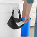 A person using a Lavex black trash bag dispenser to put a bag in a white trash can.