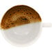 A white porcelain RAK breakfast cup filled with coffee with brown foam on top.