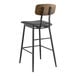 A Lancaster Table & Seating black metal and wood barstool with black vinyl padded seat and espresso wood backrest.
