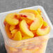 A plastic container filled with IQF organic sliced peaches.