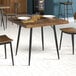 A Lancaster Table & Seating standard height table base with a wooden top and chairs around it.