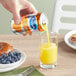 A hand pouring Ocean Spray orange juice from a can into a glass.
