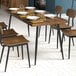 A Lancaster Table & Seating black standard height table base with a wooden top in a restaurant dining area.