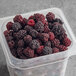 A plastic container of IQF organic whole blackberries.