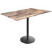 A Holland Bar Stool rustic wood bar height table with a black round base.