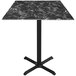 A Holland Bar Stool black marble table with a metal cross base.