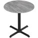 A grey circular Holland Bar Stool EuroSlim table top on a round table with a black cross base.