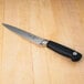 A Mercer Culinary Genesis forged flexible fillet knife with a black handle on a wooden table.