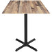 A Holland Bar Stool rustic wood bar table with a black metal base.