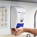 A white and blue SC Johnson Professional hand, hair, and body wash dispenser on a wall.