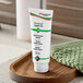 A white tube of SC Johnson Professional Stokolan Light PURE skin conditioning cream with black text and a green label on a wooden tray.