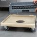 A grey plastic Vollrath rack dolly base on a table with a white tray with a hole in it.